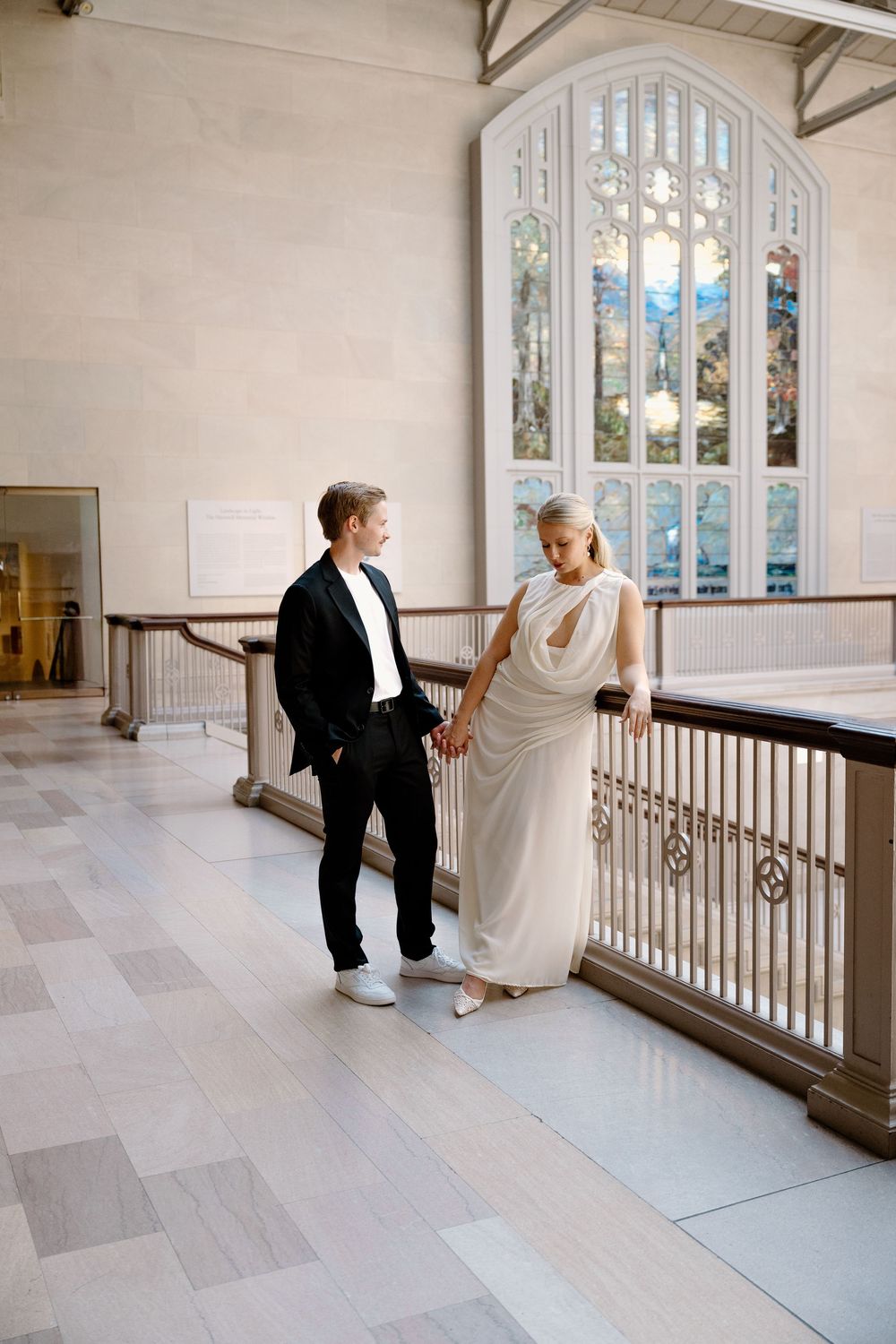 A series of romantic wedding photos taken in a bright indoor space with arched windows and wooden railings.