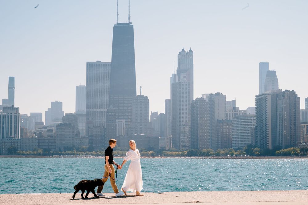 Wedding couple poses along Chicago's lakefront with the skyline and a black dog in the background.