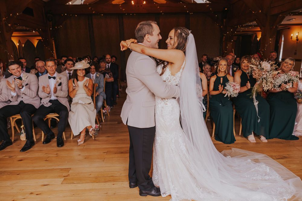 Wedding couple performs their first dance as guests watch from the sides during an elegant indoor reception.