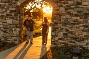 Couple silhouetted in stone archway during golden sunset.