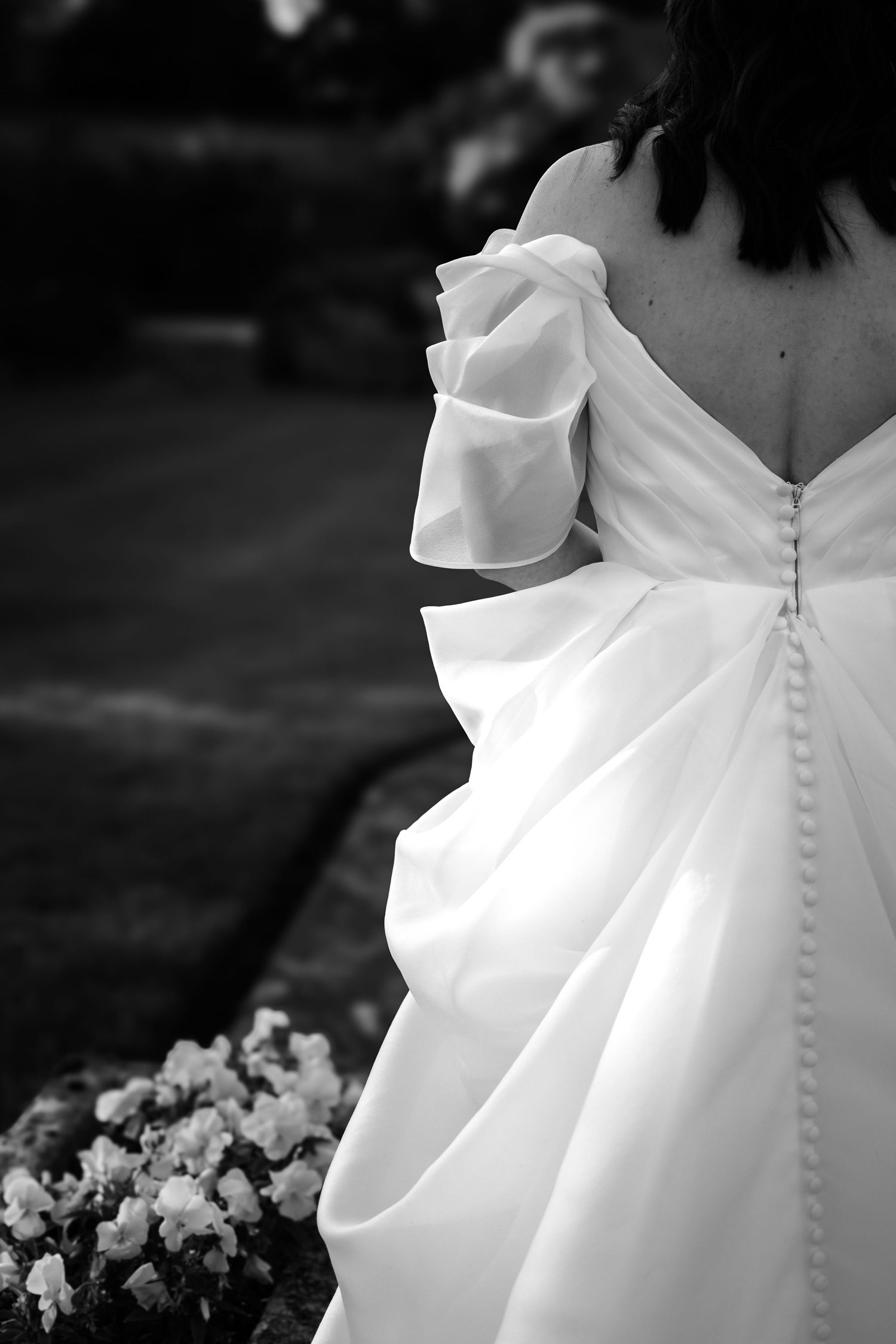 Close-up details of elegant white wedding dress buttons and fabric.