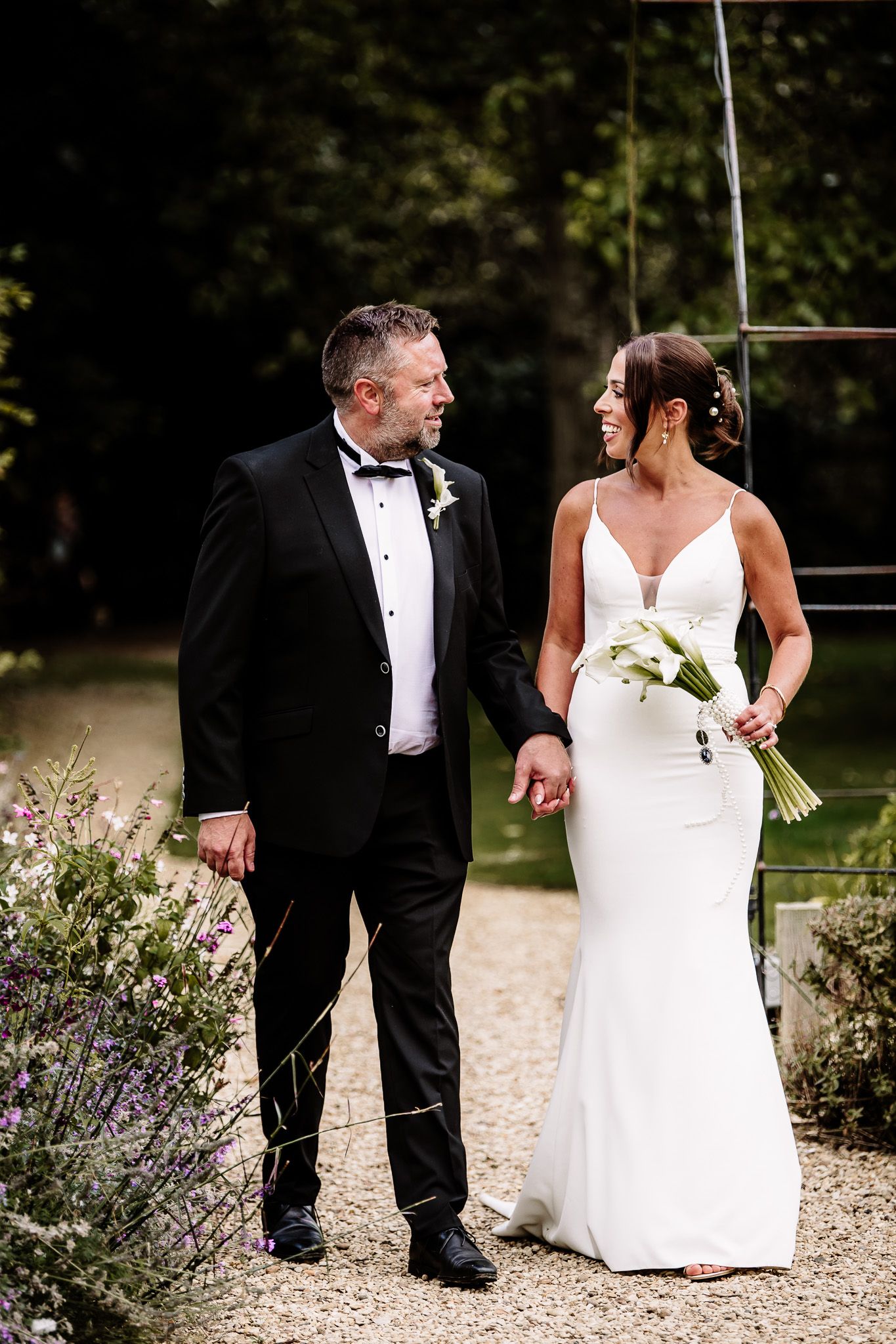 Bride and groom walking together through a garden path with lavender flowers.