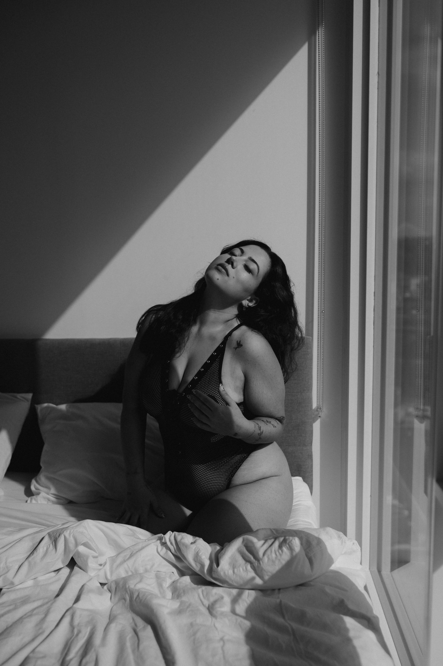 Artistic black and white portrait series with dramatic window lighting.