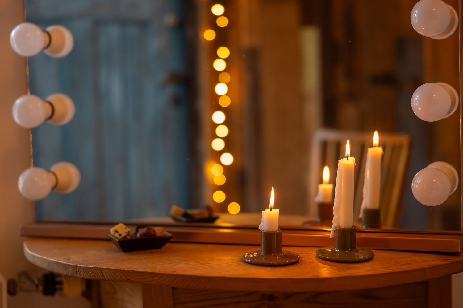 Warm candlelight illuminates a cozy dining room with glowing string lights and white lanterns creating an intimate ambiance.