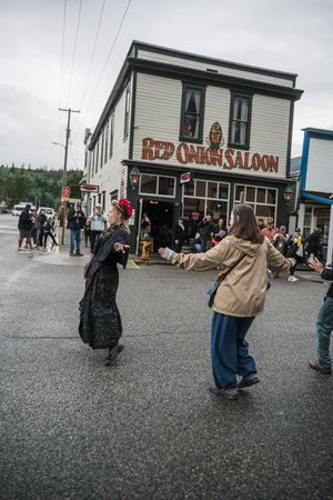 Two women in costumes dance outside the historic Red Onion Saloon in Skagway Alaska.