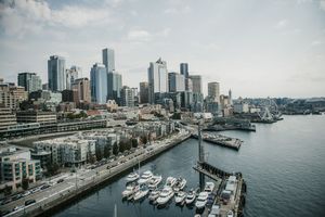 Aerial view of Seattle waterfront skyline with marina, luxury yachts, and modern skyscrapers on a cloudy day.