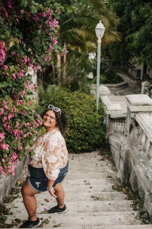 A stone pathway surrounded by pink bougainvillea flowers and lush tropical greenery creates a romantic garden setting.