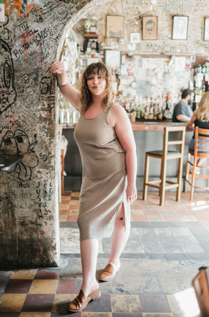 A person in a beige dress poses in a sequence of dance-like movements against a graffiti-covered wall in a restaurant.