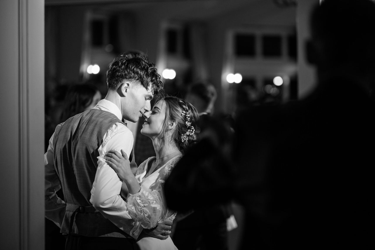 Black and white photo of a couple sharing an intimate moment during their first dance at a wedding reception.