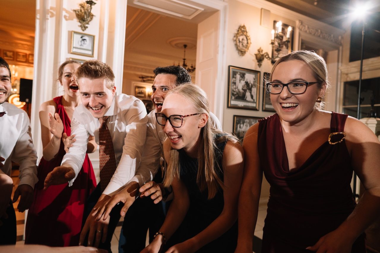 Group of young adults laughing and celebrating at an elegant wedding reception party.