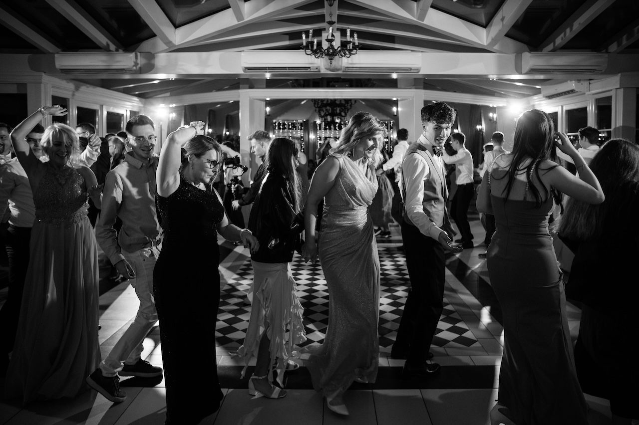 Black and white wide shot of wedding guests filling dance floor at elegant reception.
