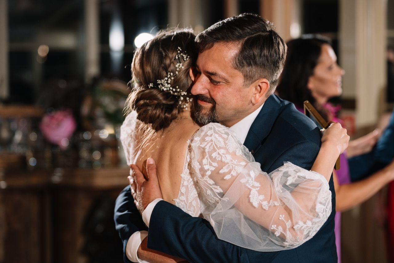 Bride sharing a warm emotional hug with her father on the wedding dance floor.