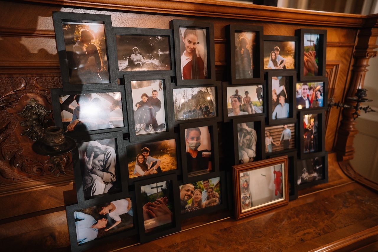 Collection of framed couple photos displayed on wooden surface at wedding venue.
