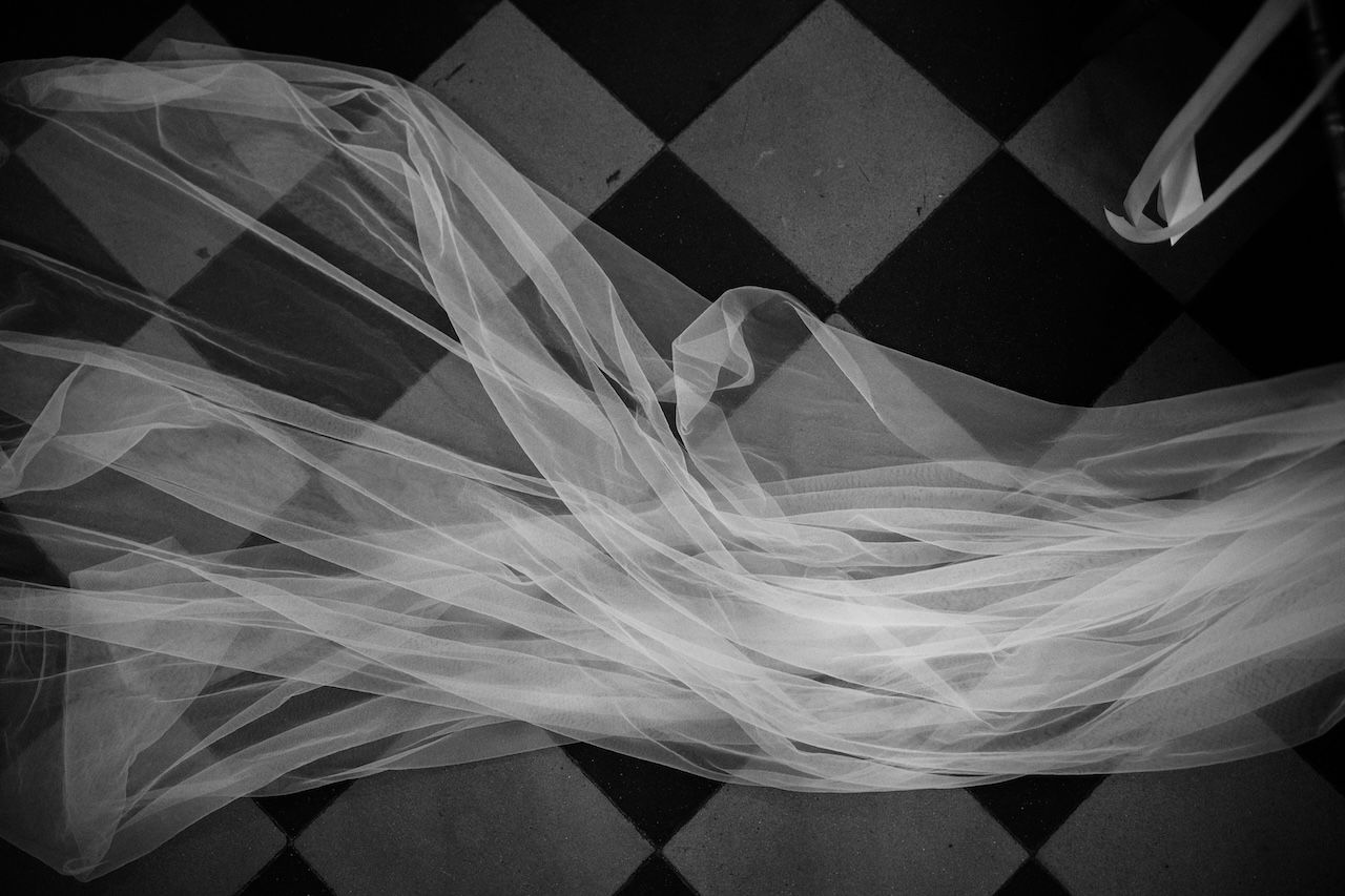 Artistic black and white overhead shot of flowing bridal veil on checkered floor.