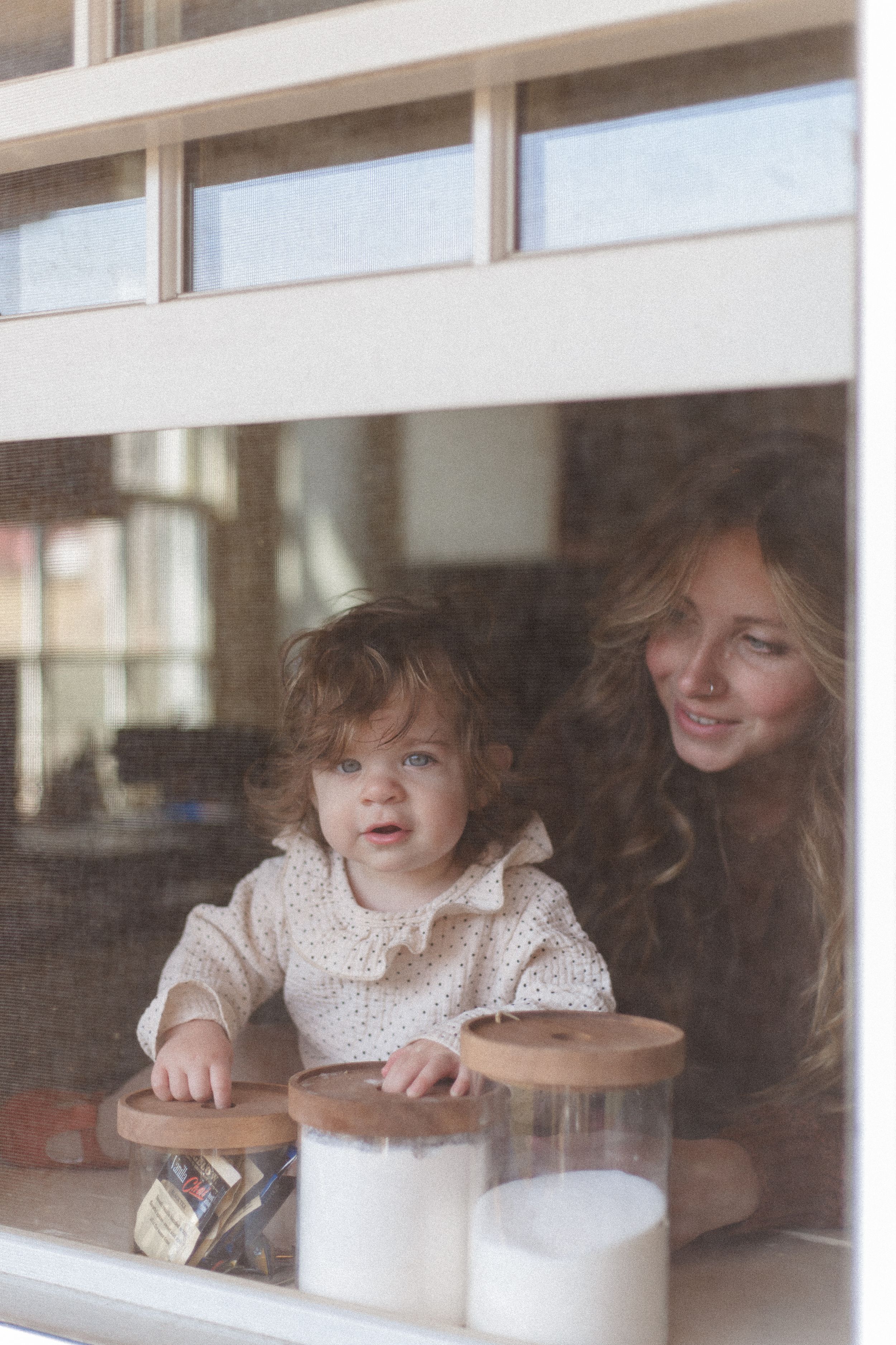 Two people enjoy hot beverages while sitting by a window in a cozy indoor setting.