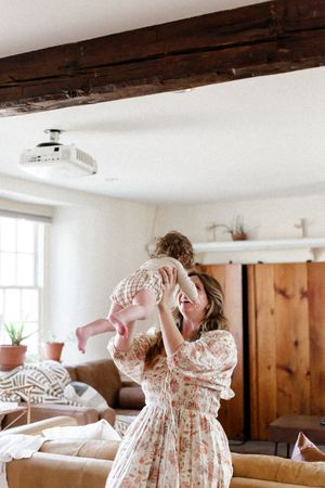 A sequence of photos showing someone dancing and twirling in a white floral dress in a sunlit room.