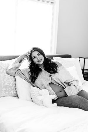 Black and white photo series showing a relaxed figure lounging on white bedding in casual attire.