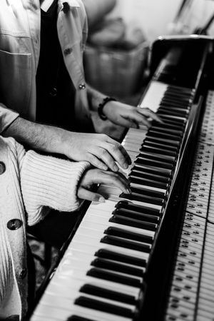 Close-up shots of hands playing piano keys in black and white.