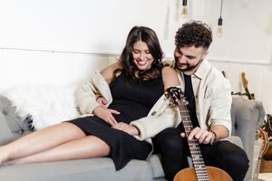 Couple in black clothing share intimate moments on white furniture in a romantic lifestyle photoshoot series.