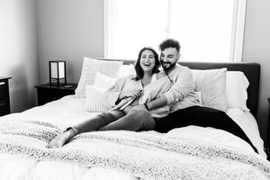 A sequence of four black and white photos showing playful moments on a bed with pillows and blankets.