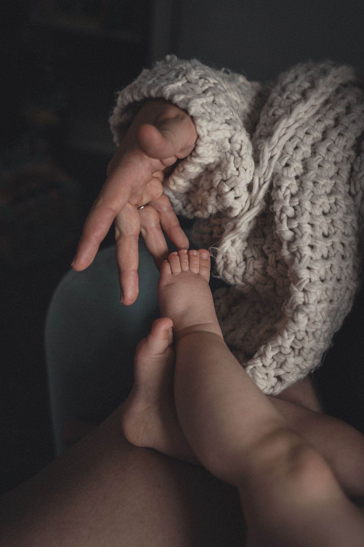 La main d'une maman effleure le tout petit pied de son bébé