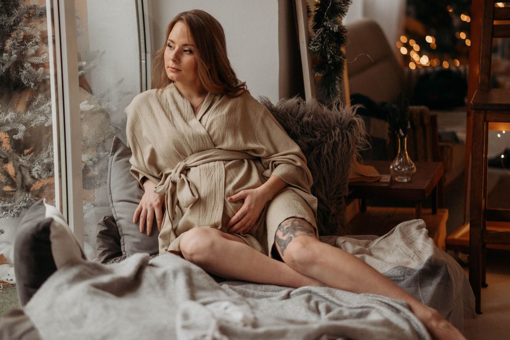 Person in neutral tones reclining on textured bedding with warm ambient lighting.