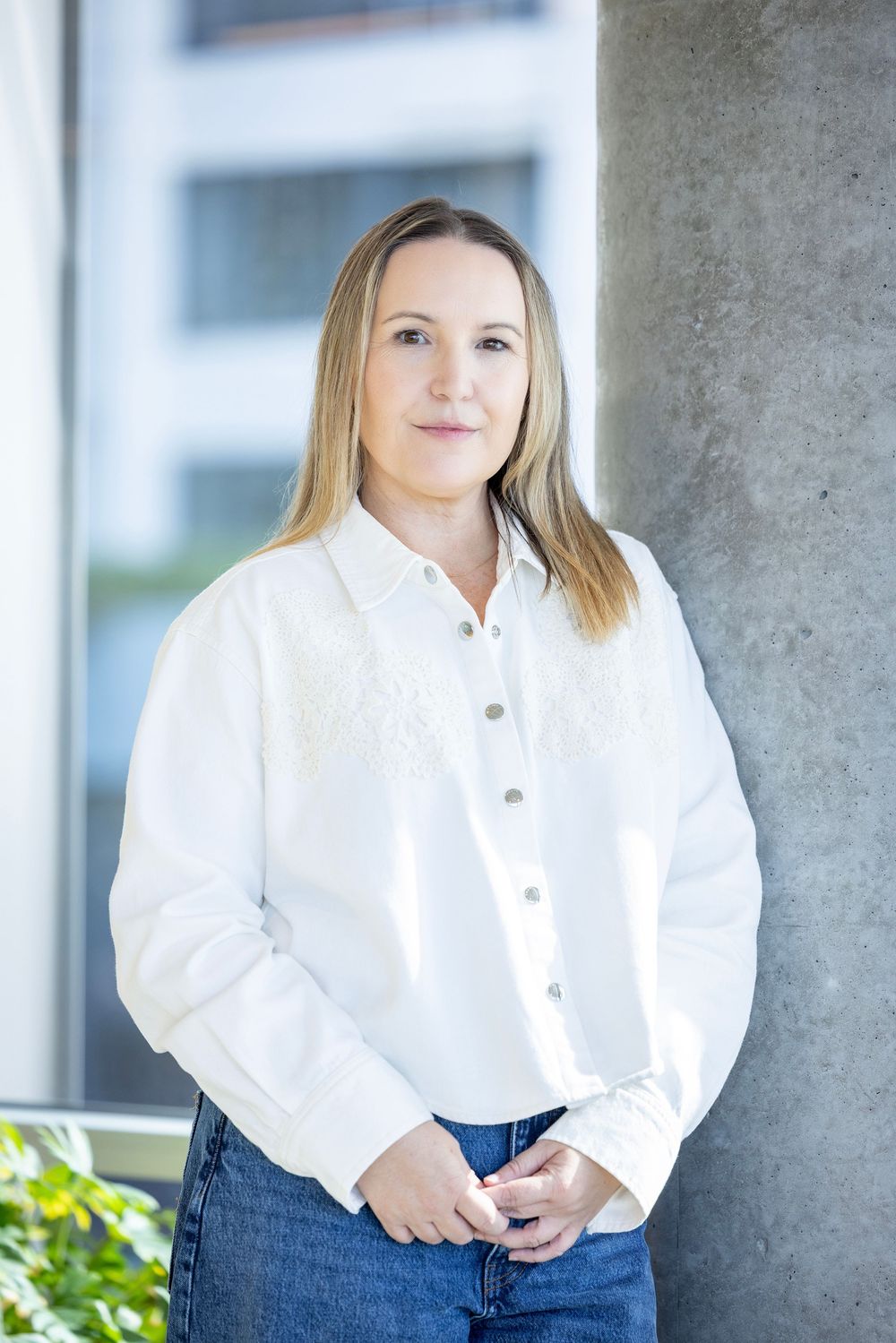 Portrait of a lady in a white shirt leaning against a concrete column