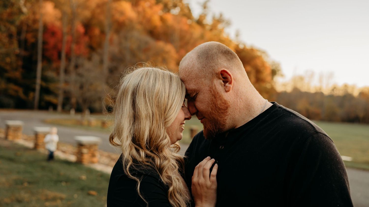Intimate fall photo session with couple standing close together surrounded by autumn colors.