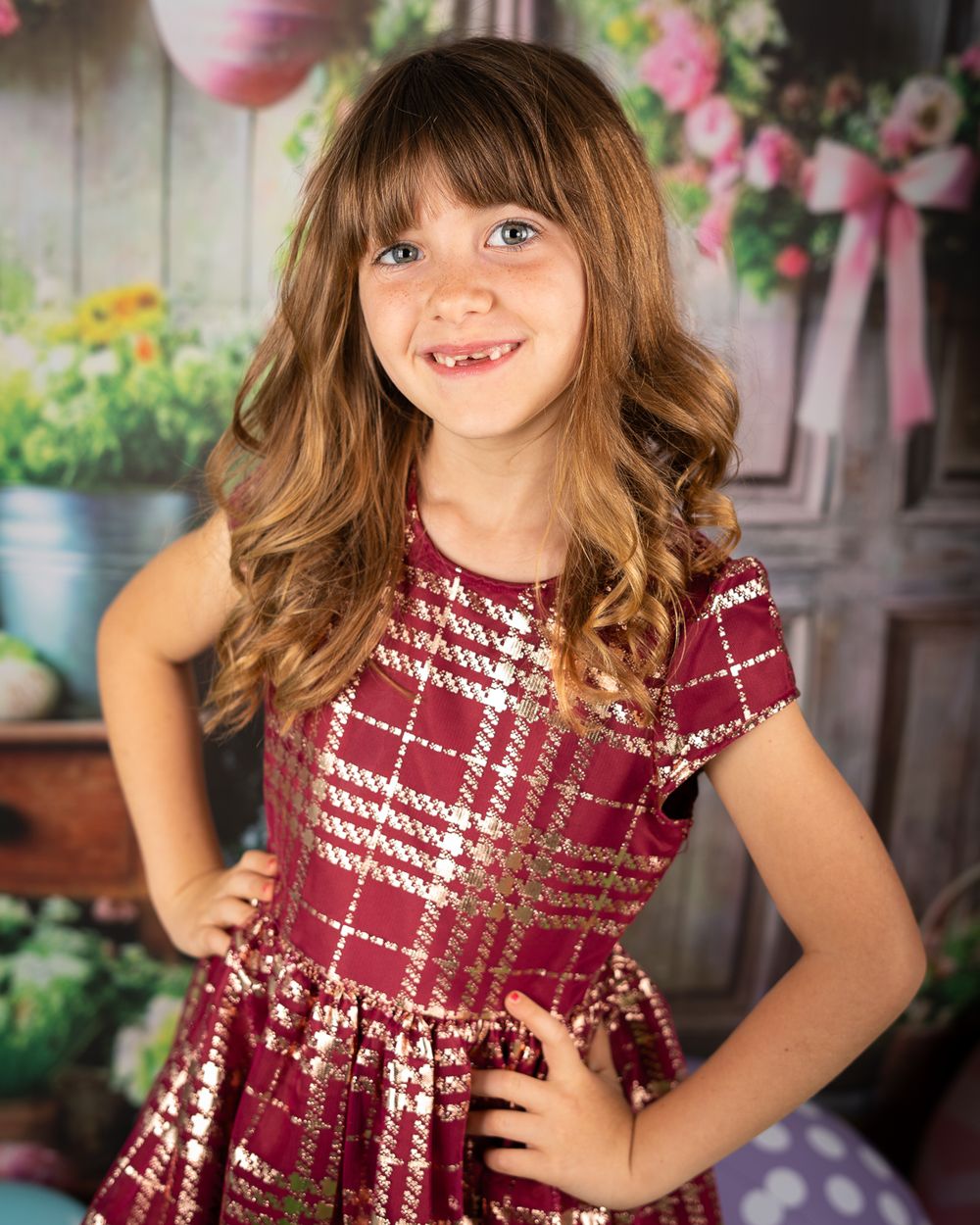 Studio portrait with floral backdrop featuring burgundy plaid dress and natural poses.
