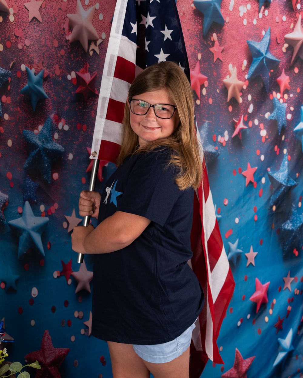 Patriotic portrait session with American flag and star backdrop in casual attire.