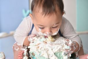 A cake smash photo session showing messy fun with turquoise frosting.