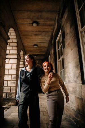 A group poses playfully in a rustic corridor with brick walls and wooden ceiling beams.