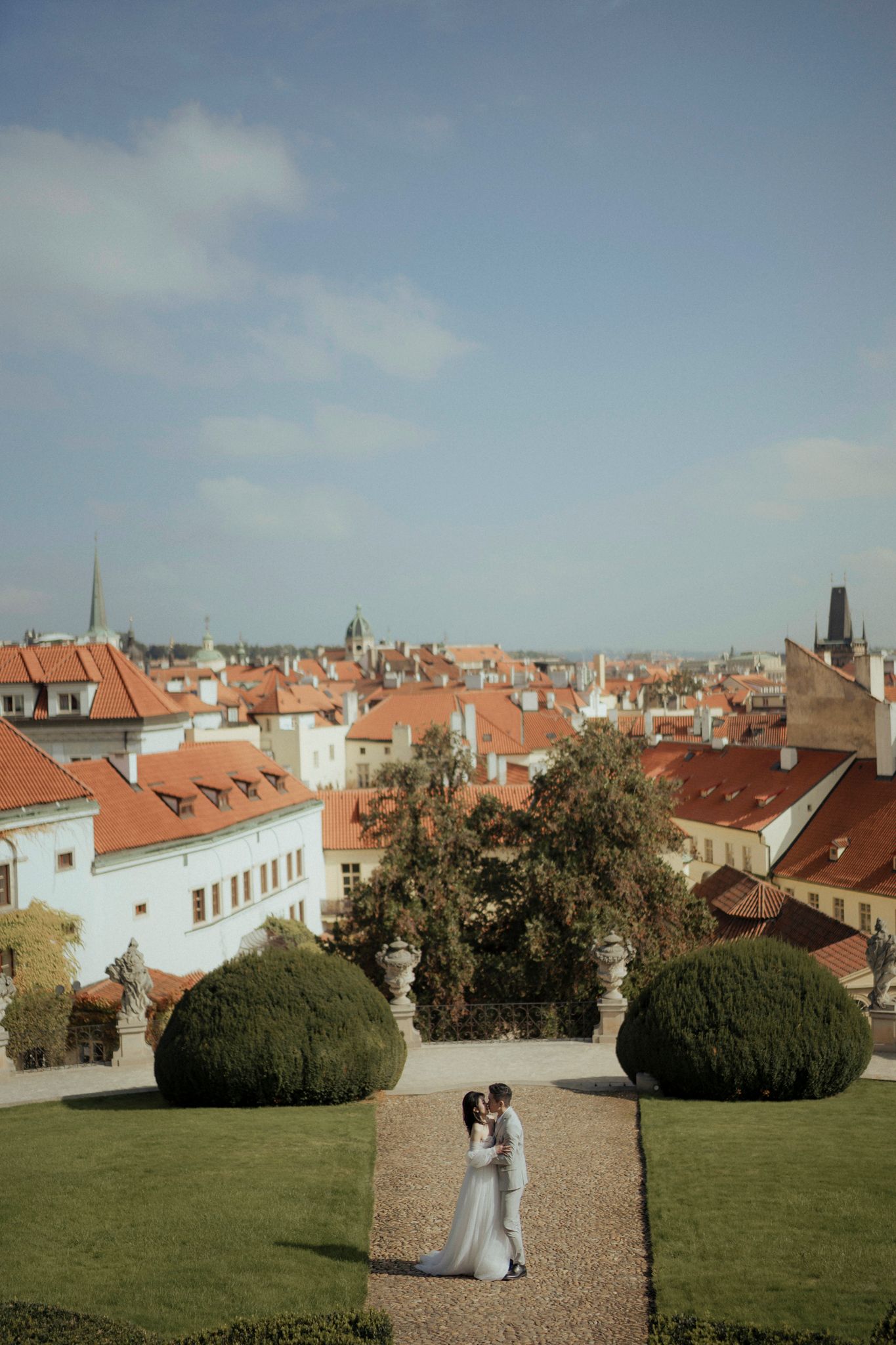Aerial view of historic European city with red rooftops and manicured garden.