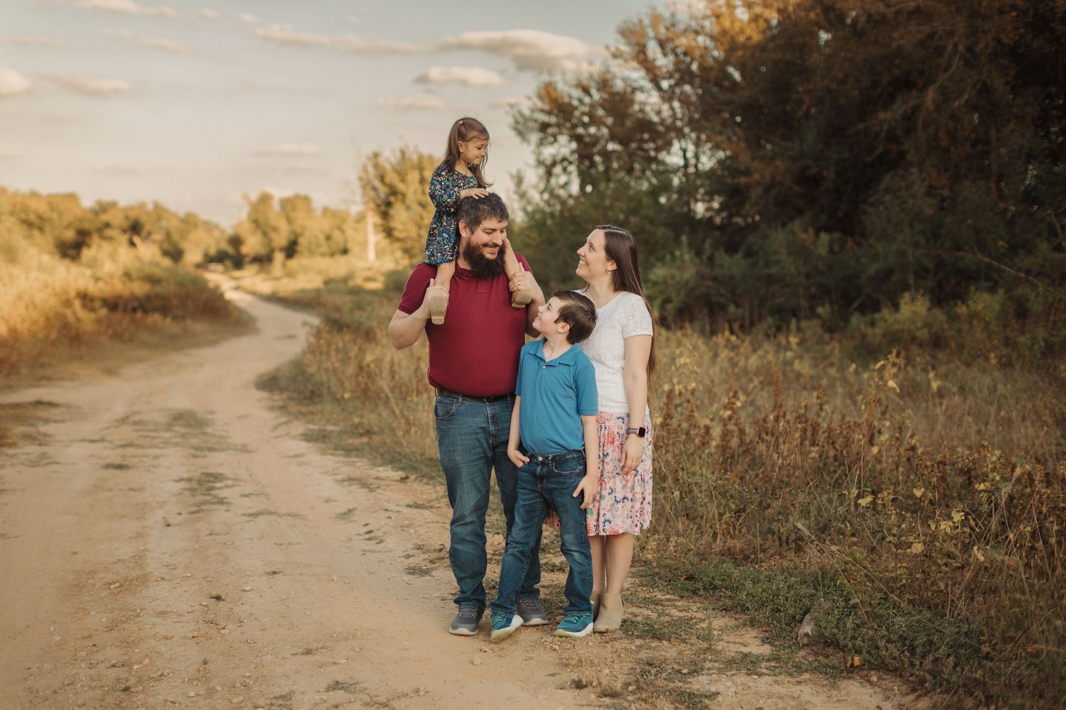 Outdoor family portraits captured on a winding dirt path at sunset.