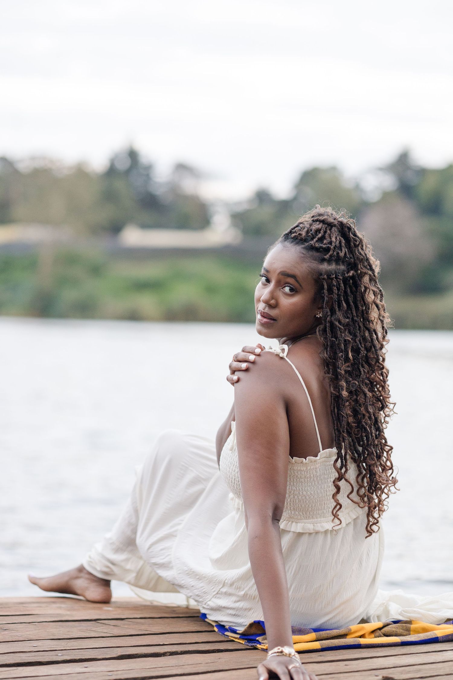 Full-length portrait of a lady by the lake in Naishola Gardens. She's seated on the ledge. Ikigu George Photography.