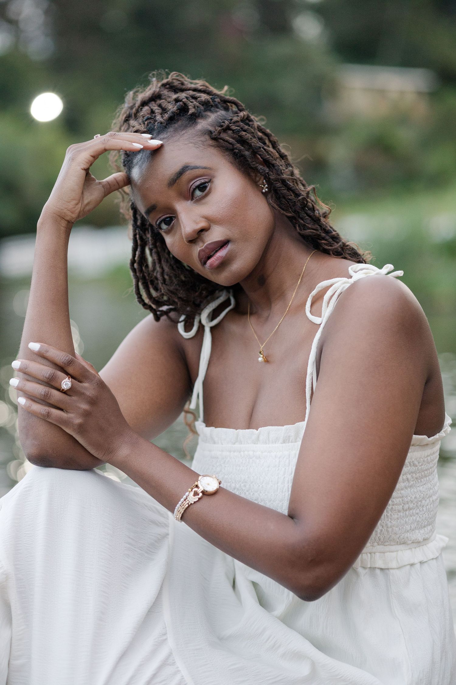 Portrait of a lady in white dress, by the lake in Naiposha Gardens. She has a somber look on her face. Ikigu George Photography.