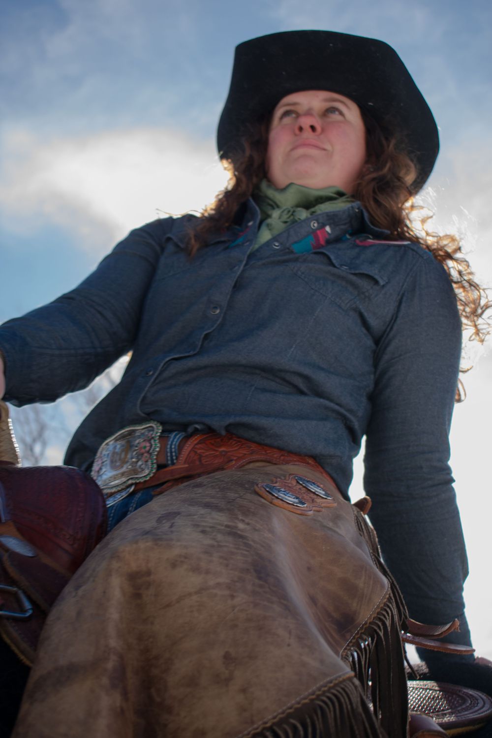 Cowgirl sitting on horse staring stoically into the distance