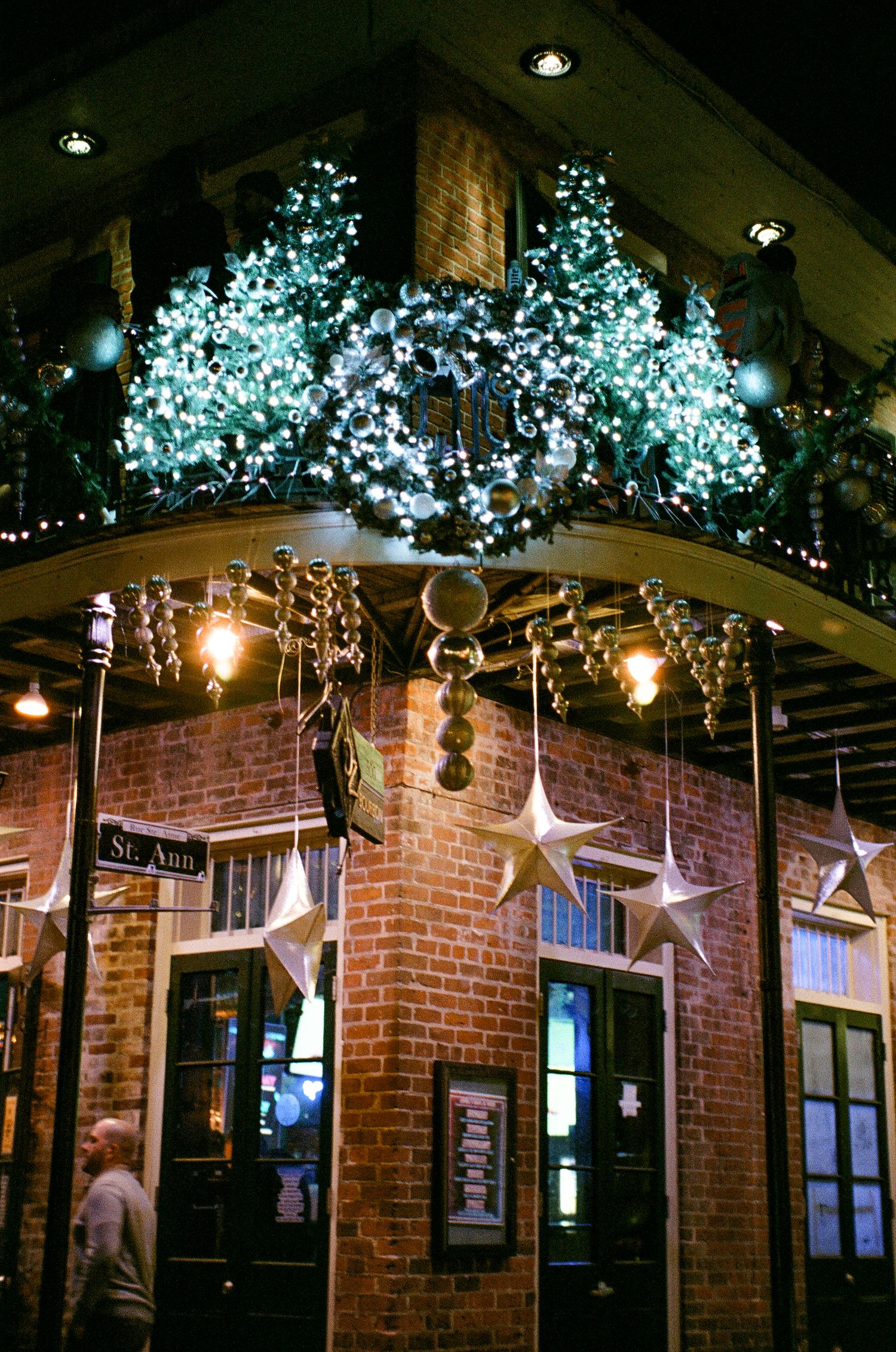Festive blue LED lights and hanging star decorations adorn the exterior of a brick building.
