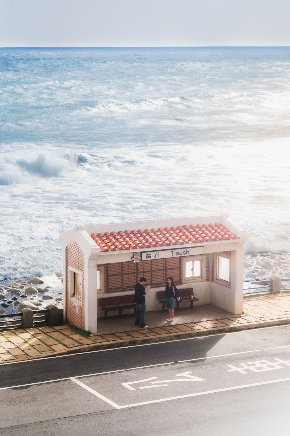 A series of pink bus stops along a coastal road with ocean waves in the background, showing different viewing angles.