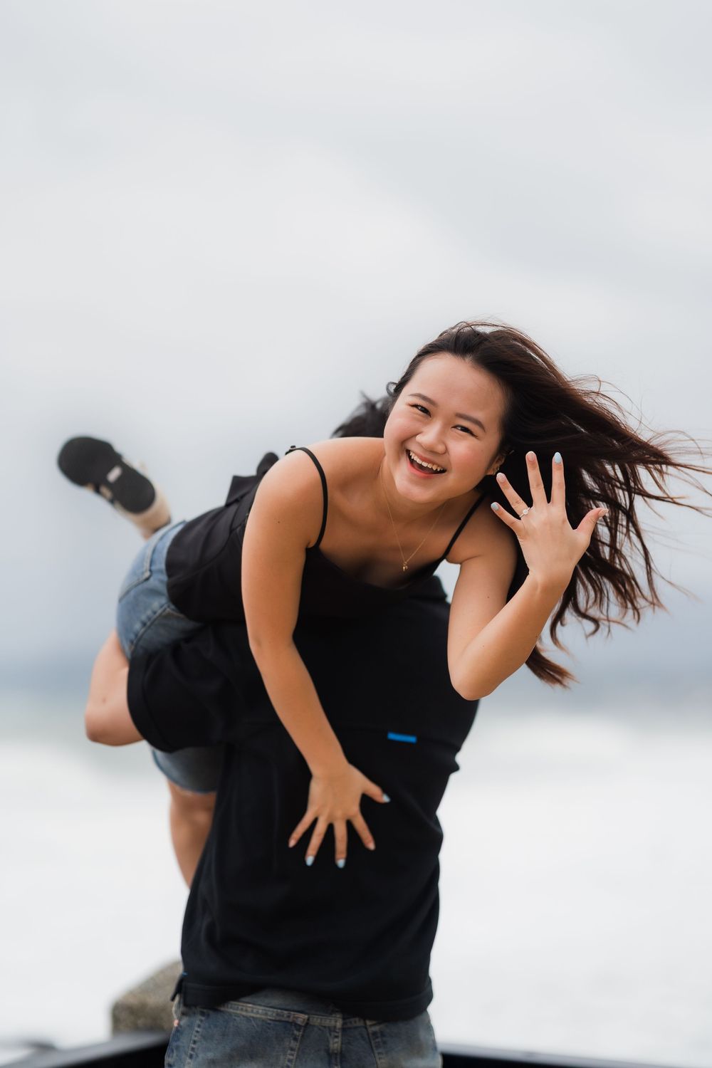 A series of playful jumping poses in casual black outfits against a cloudy sky background.