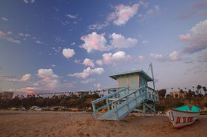 Fine art landscape photograph of a lifeguard tower on Santa Monica beach California with glowing pink clouds and a blue sky. Wall art.