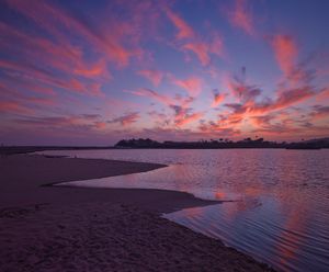 Fine art landscape photograph of Malibu beach  in California at sunset with brilliant pink clouds and a blue sky. Wall art