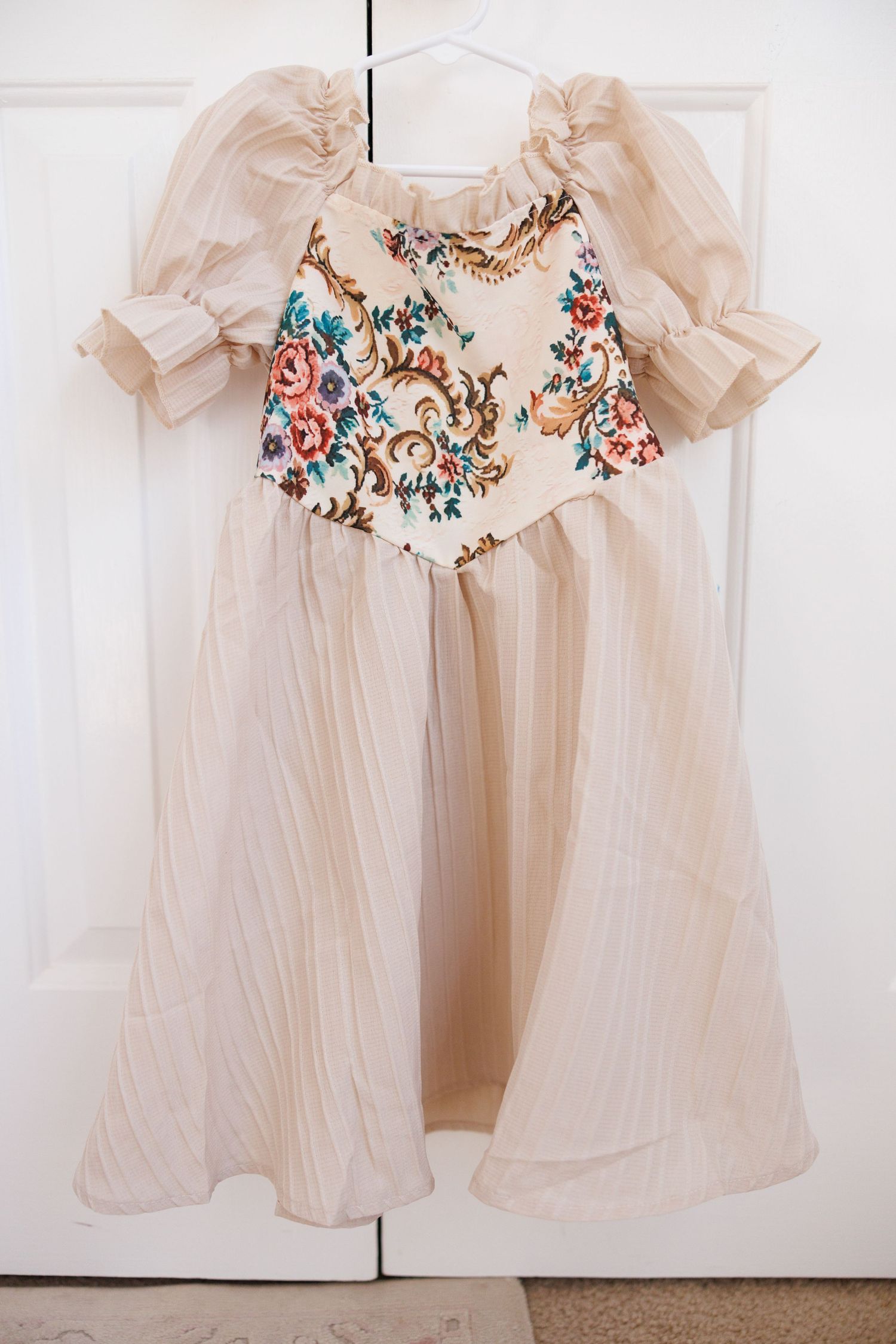 A floral print baby sleeper garment with red and brown pattern shown from multiple angles on a light background.