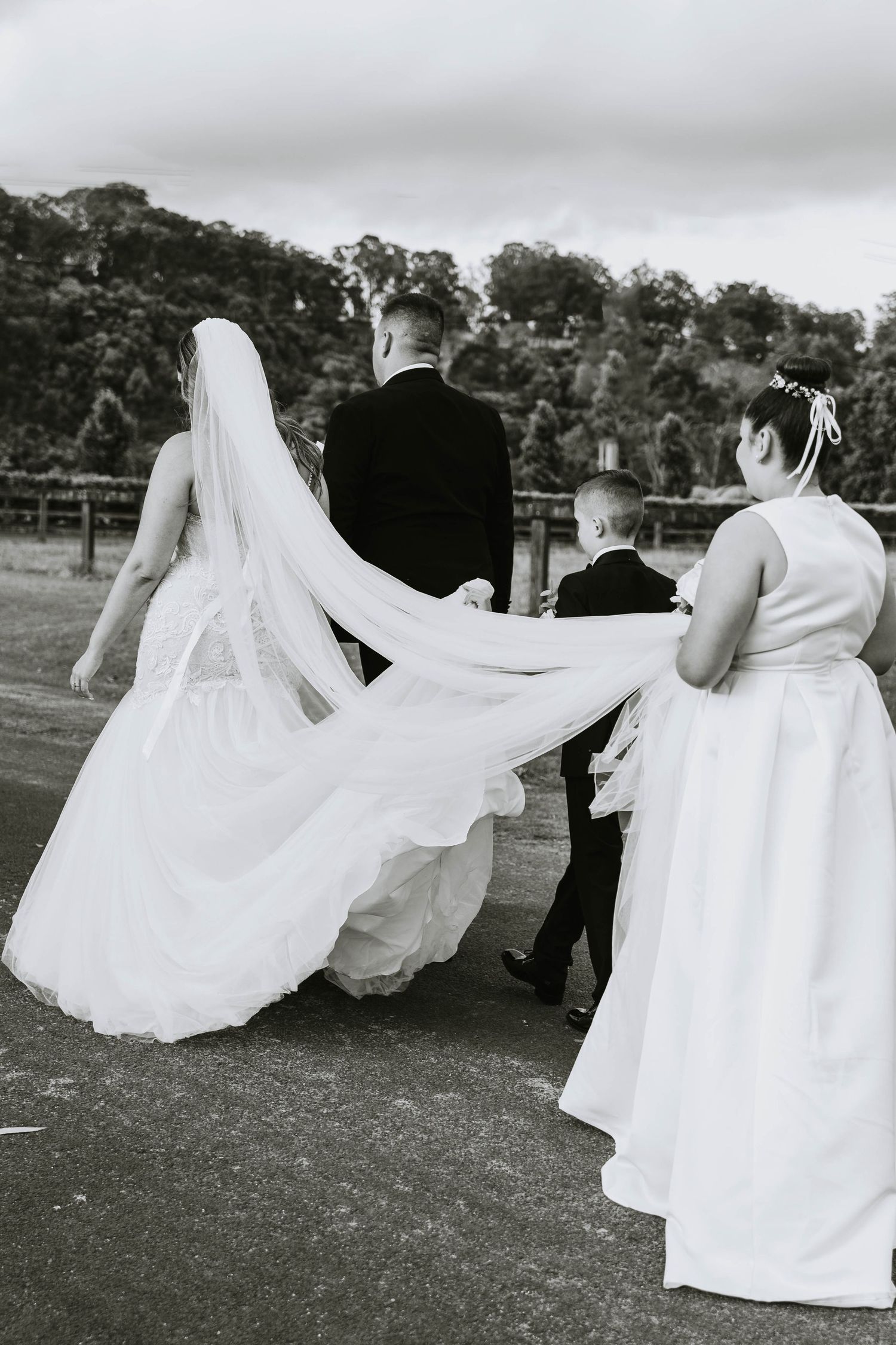 Wedding dress flowing dramatically in black and white as couple moves across field.