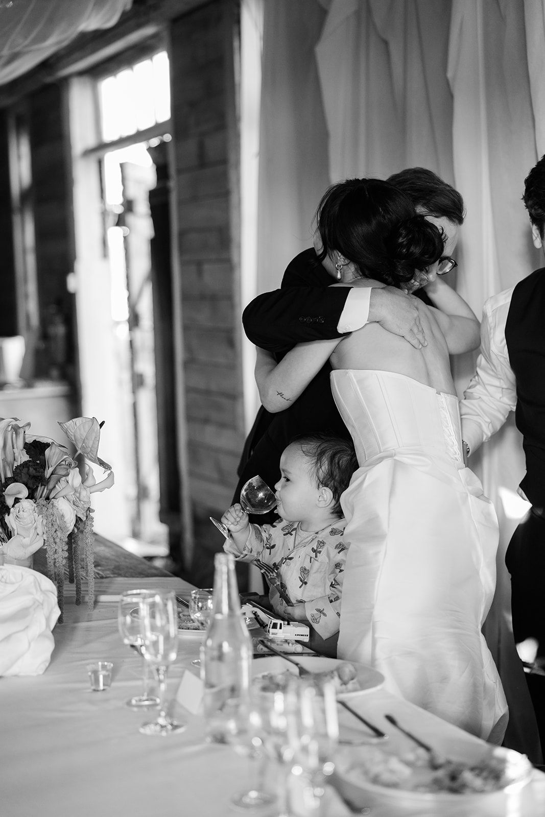 Black and white wedding reception photo series showing intimate candid moments between guests at an elegant dining table.