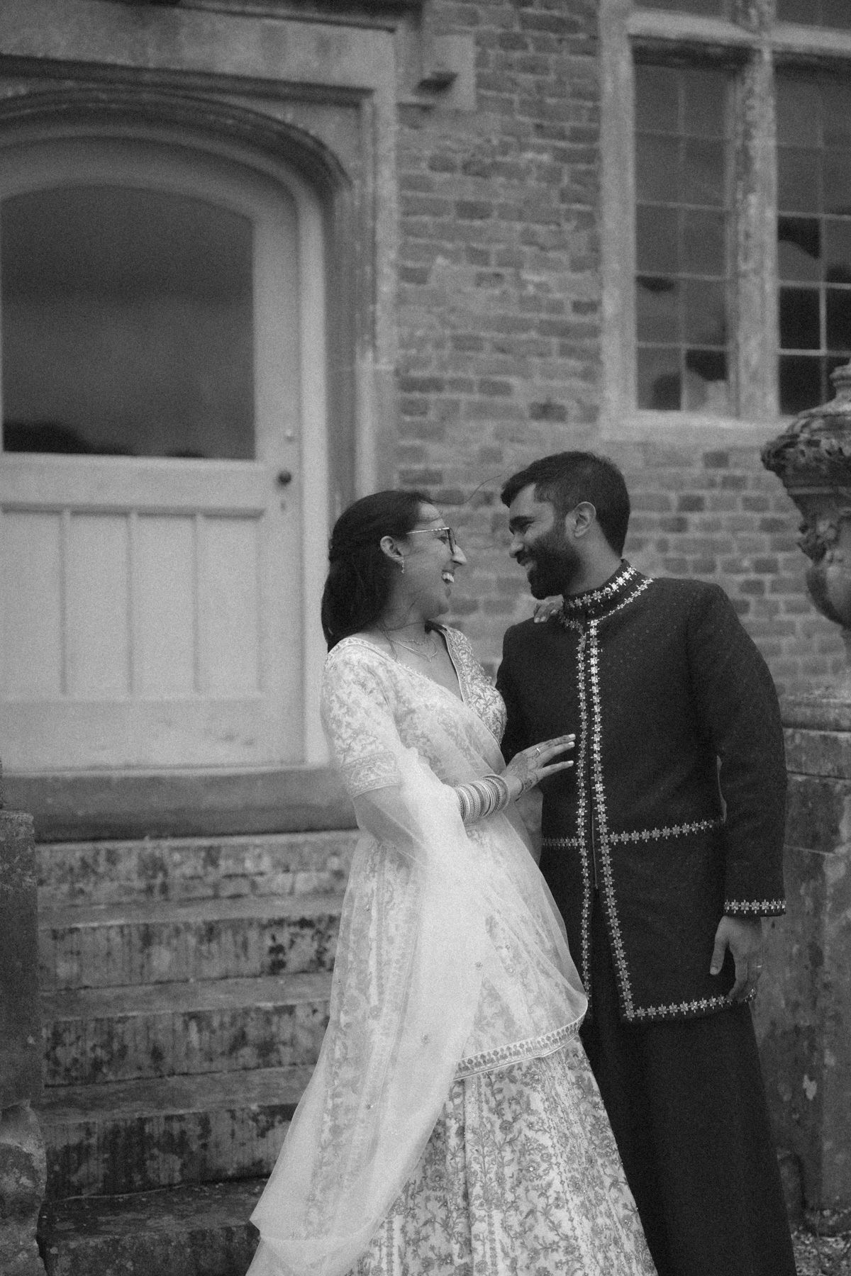 A romantic black and white photo series showing a couple in vintage wedding attire against a brick wall.