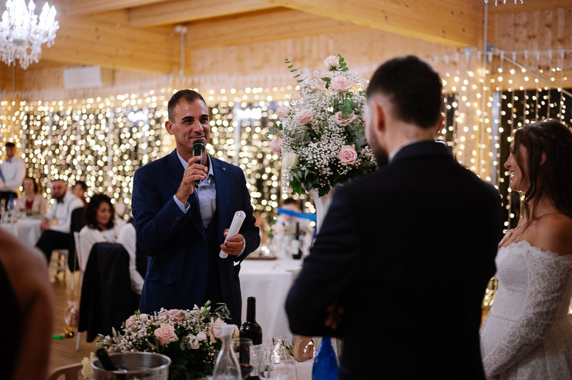 Wedding reception venue decorated with twinkling string lights and white table settings in a rustic wooden interior.