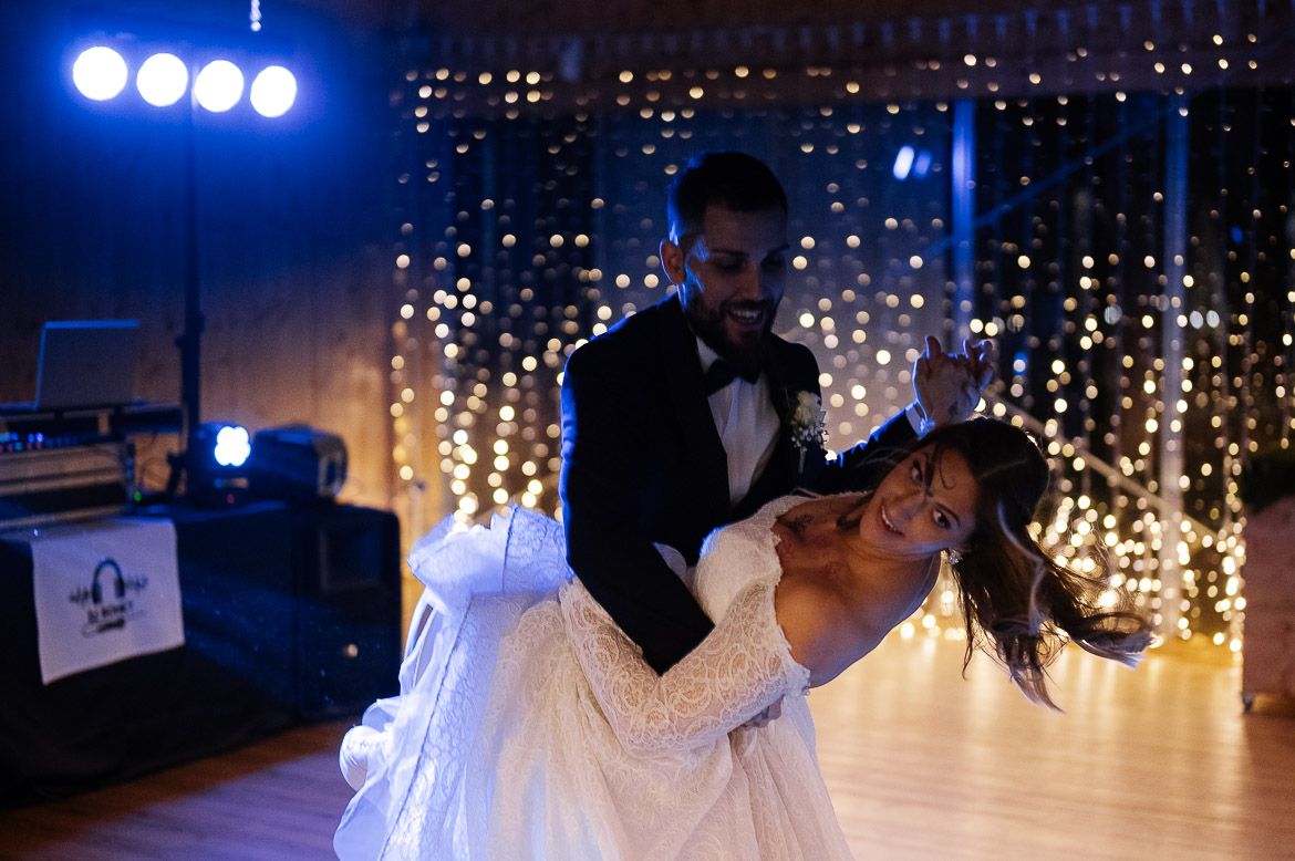 Wedding reception dance floor with dramatic blue lighting and glowing string lights in background.