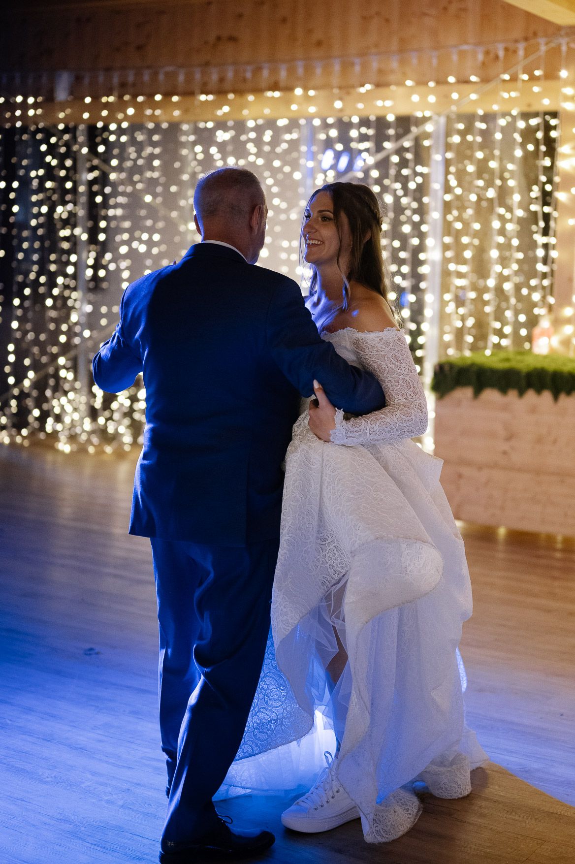 Romantic first dance moment in a barn venue illuminated by warm string lights.