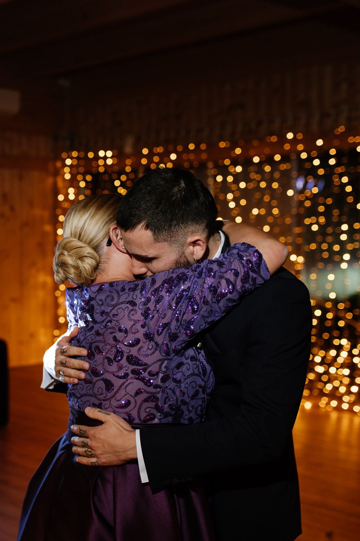 An intimate dance moment at a wedding reception with warm string lights in the background.